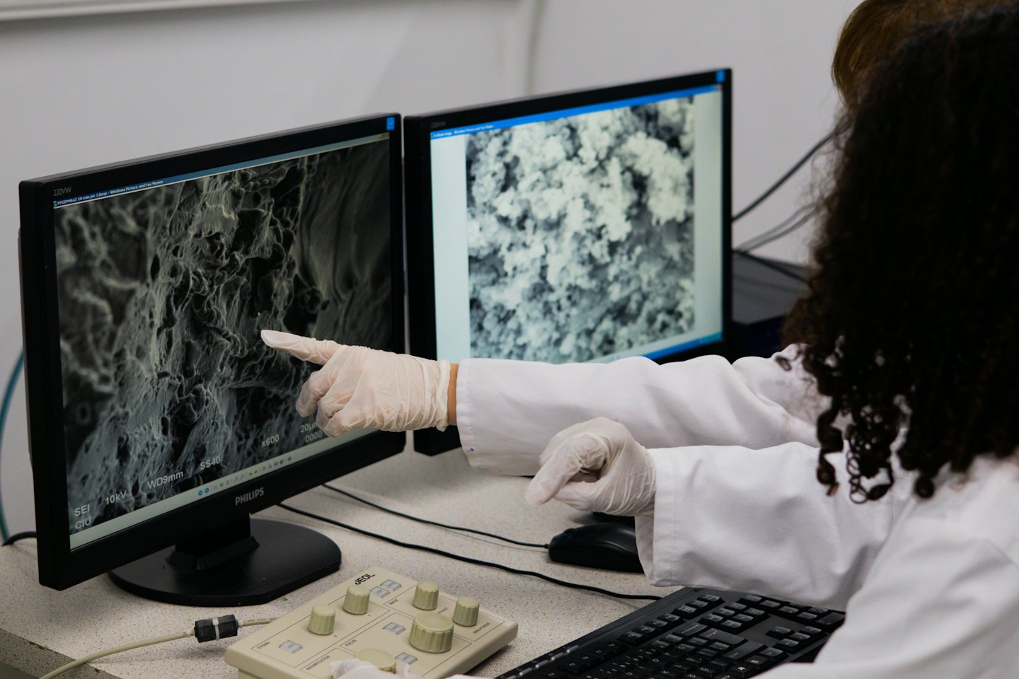 Investigador analiza imagen de microscopio electrónico en monitores de computadora en laboratorio.
